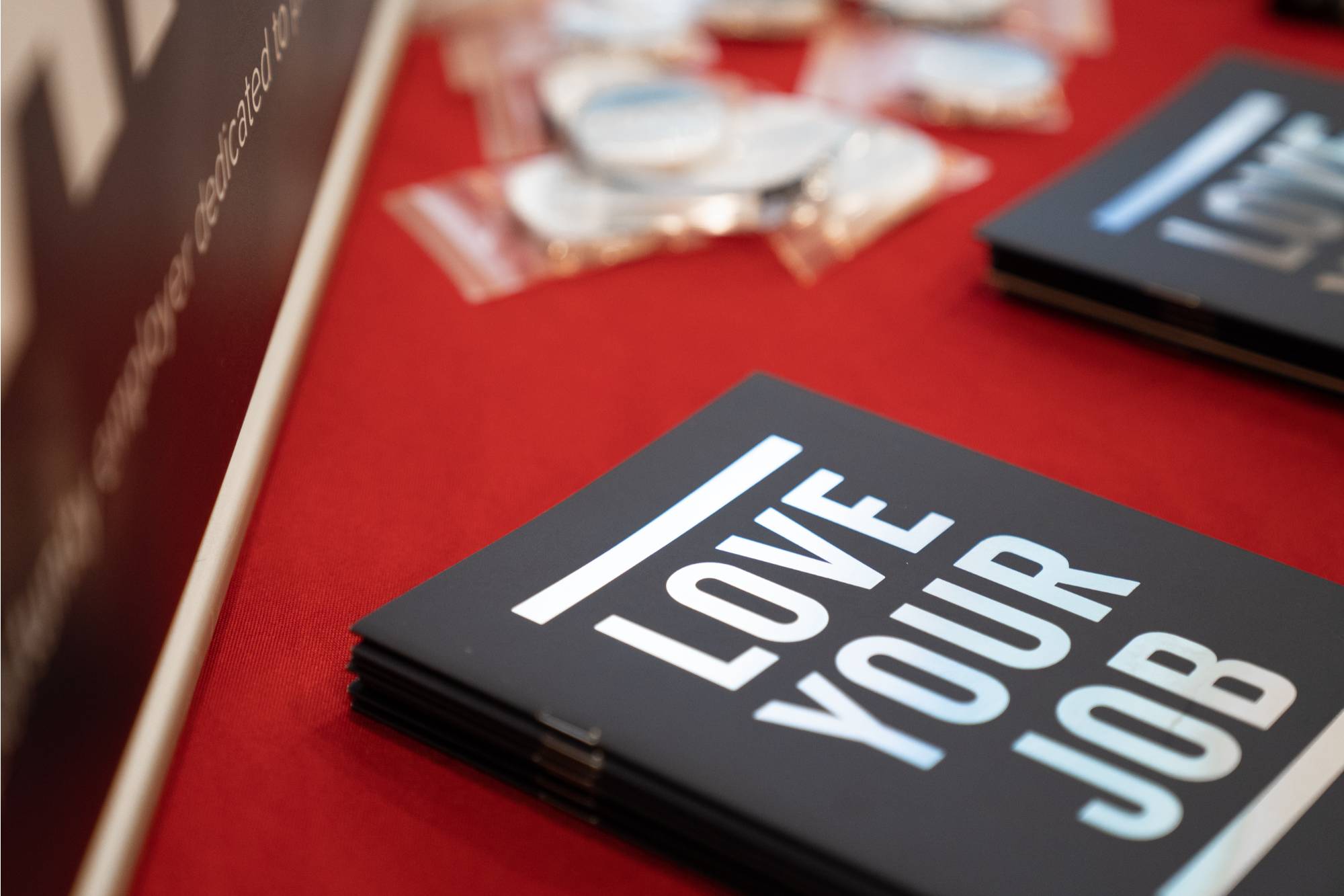 A black and white book saying "Love your job" on a red table cloth